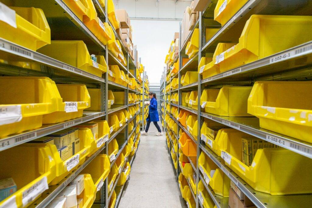 Distribution center with yellow plastic crates on white floor tiles Photo by Adrian Sulyok